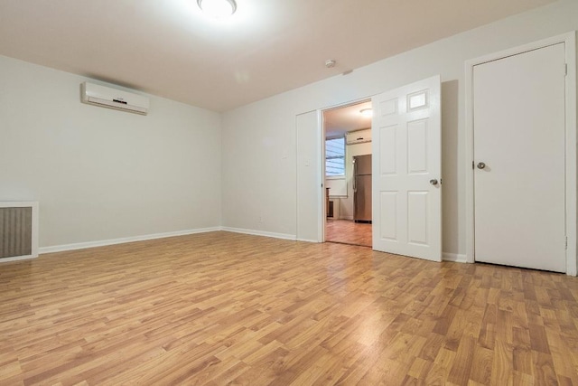 unfurnished room with light wood-type flooring and a wall unit AC