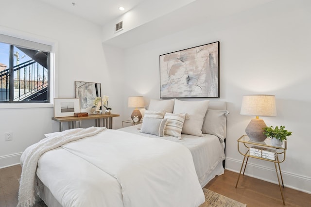 bedroom featuring baseboards, wood finished floors, and visible vents