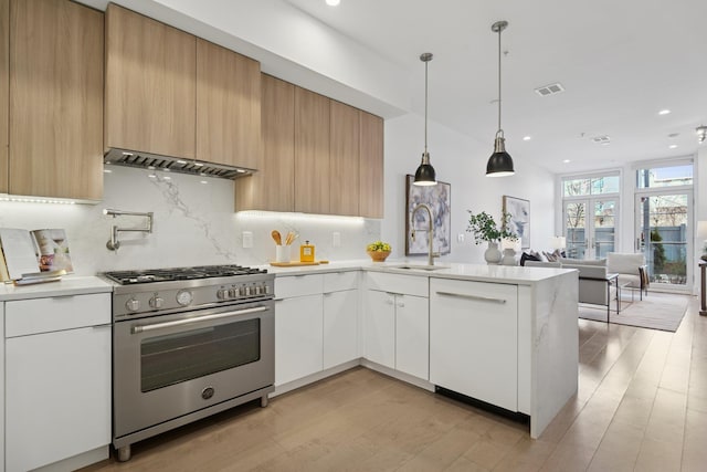 kitchen with modern cabinets, light countertops, high end stove, and a sink