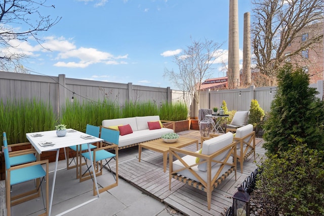 wooden terrace with outdoor dining area, an outdoor living space, and a fenced backyard