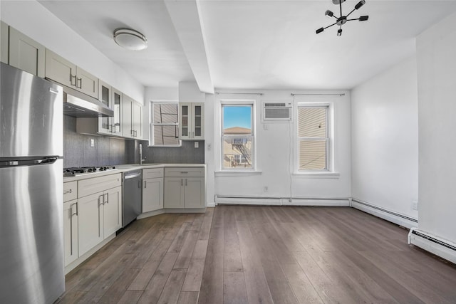 kitchen featuring extractor fan, stainless steel appliances, dark wood-type flooring, light countertops, and glass insert cabinets