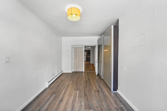 hallway with a baseboard heating unit, dark wood-type flooring, ornamental molding, and baseboards