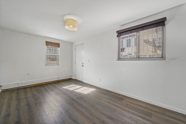 empty room with a baseboard radiator, dark wood finished floors, and baseboards