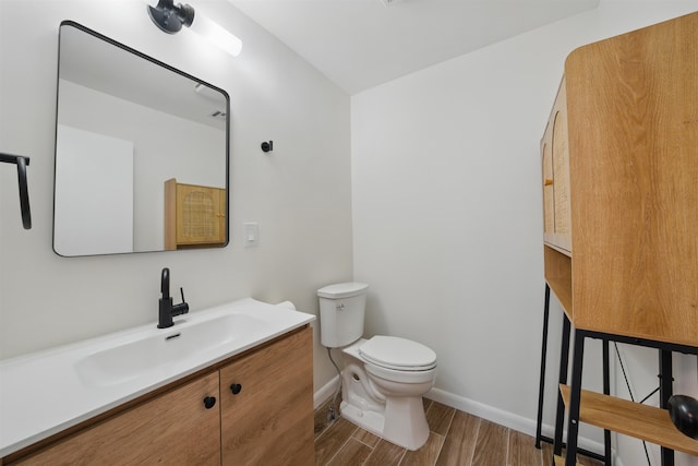 bathroom with baseboards, vanity, toilet, and wood finished floors