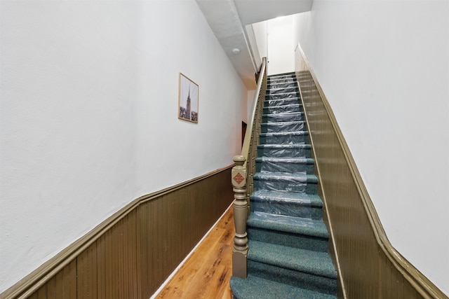 staircase featuring wood walls and wainscoting