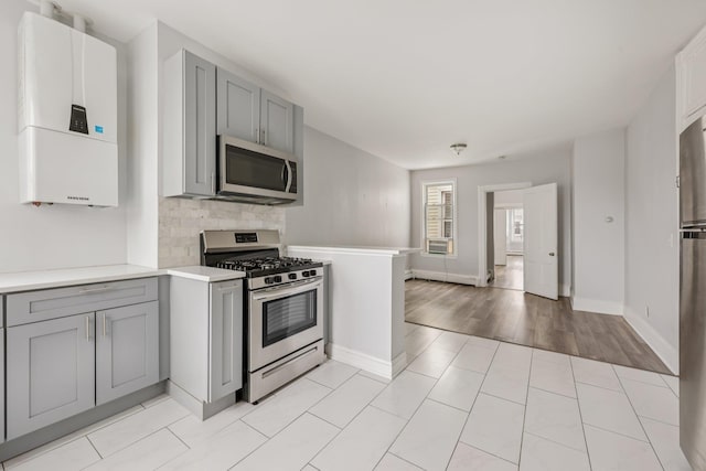 59 Monitor St Unit 3R, Jersey City, NJ 07304 - kitchen featuring stainless steel appliances, gray cabinets, light countertops, tasteful backsplash, and water heater