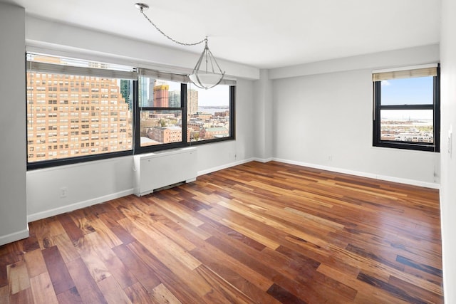 135 Montgomery St Unit 19A, Jersey City, NJ 07302 - spare room featuring radiator heating unit, plenty of natural light, and wood finished floors