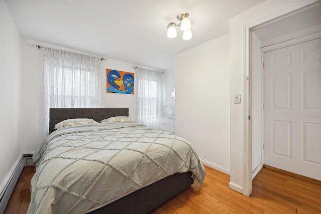 227 7th St, Jersey City, NJ 07302 - bedroom with baseboards, a baseboard heating unit, and wood finished floors