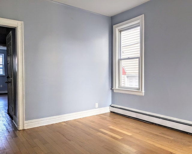 spare room featuring a baseboard heating unit and hardwood / wood-style floors