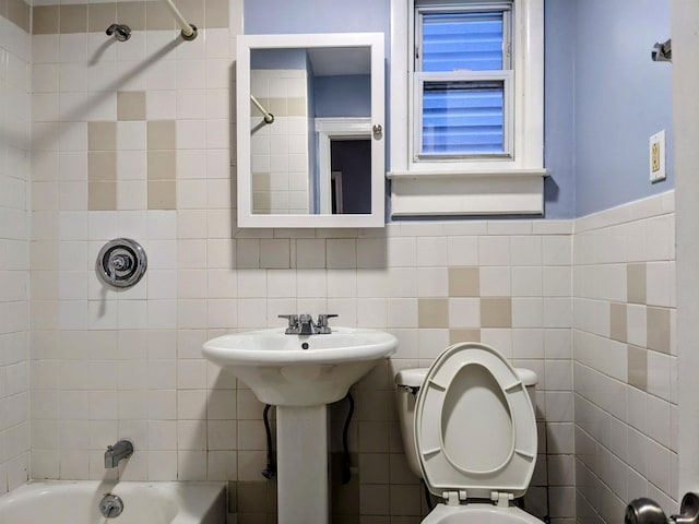 bathroom with tiled shower / bath, tile walls, and toilet