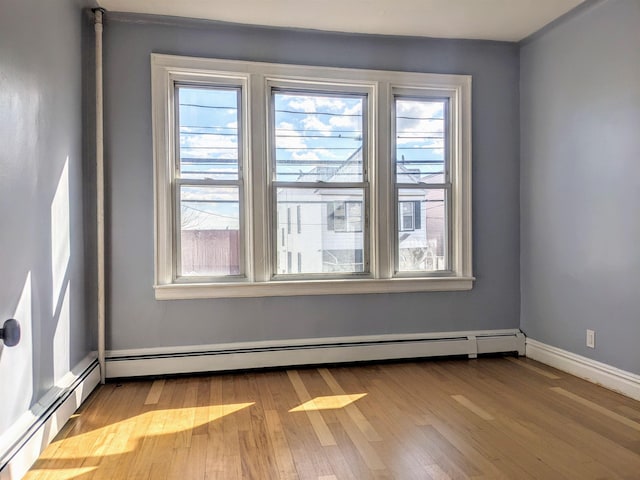 empty room featuring a wealth of natural light, light hardwood / wood-style floors, and baseboard heating