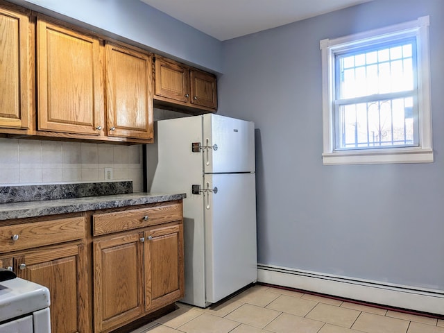 kitchen with light tile patterned flooring, decorative backsplash, white fridge, and a baseboard heating unit