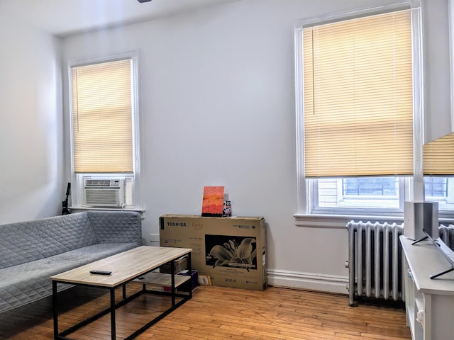 living room with cooling unit, radiator heating unit, and light hardwood / wood-style flooring