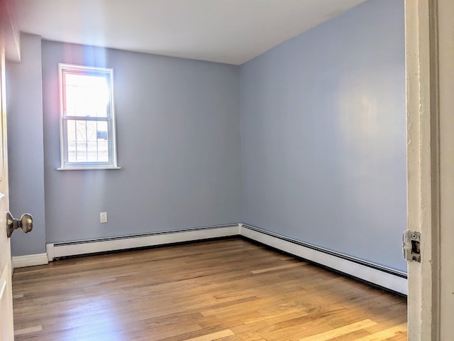 spare room featuring baseboard heating and light wood-type flooring