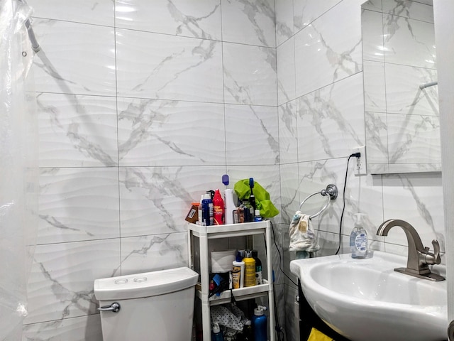 bathroom with sink, tile walls, and toilet