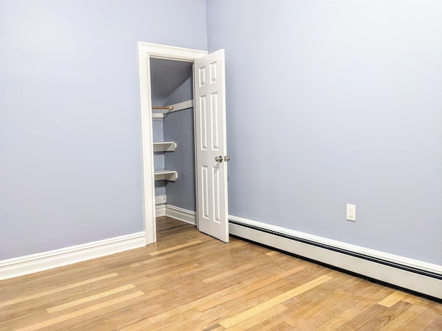 unfurnished bedroom with light wood-type flooring and baseboard heating