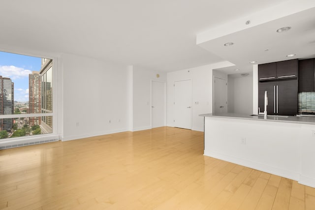 2 2nd St Unit 2106, Jersey City, NJ 07302 - unfurnished living room with light wood-type flooring, baseboards, a city view, recessed lighting, and a sink