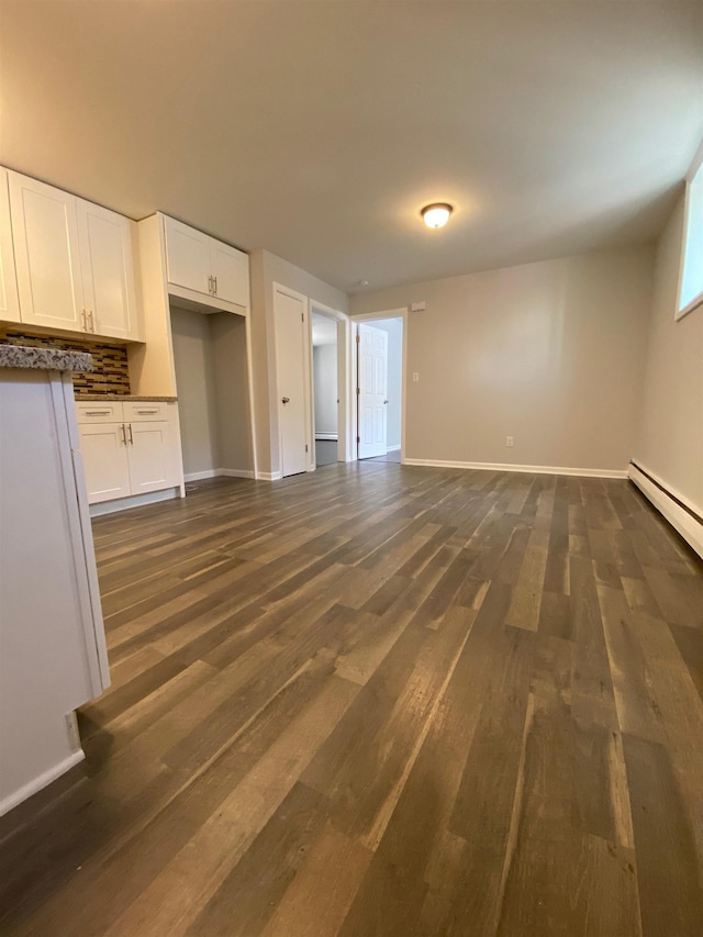 unfurnished living room featuring baseboards, baseboard heating, and dark wood-style floors