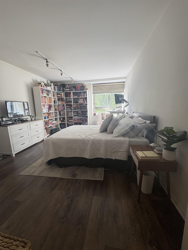 bedroom with dark wood-type flooring and track lighting