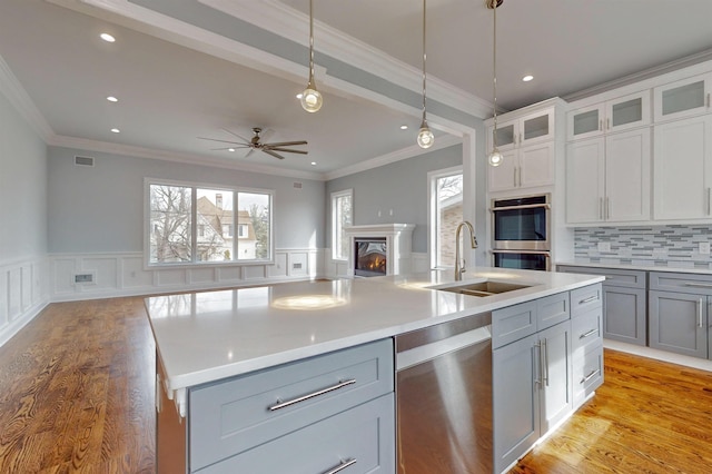 30 Cortland Pl, Cliffside Park, NJ 07010 - kitchen featuring stainless steel appliances, a sink, open floor plan, a lit fireplace, and wainscoting