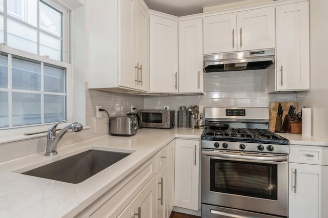 kitchen with gas range, sink, white cabinets, and backsplash