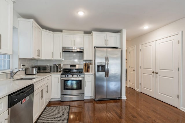 kitchen featuring sink, dark wood-type flooring, appliances with stainless steel finishes, white cabinetry, and tasteful backsplash