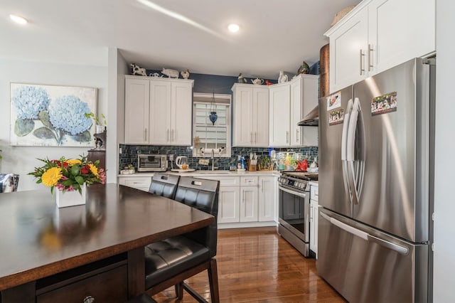 kitchen featuring appliances with stainless steel finishes, sink, white cabinets, dark hardwood / wood-style flooring, and backsplash