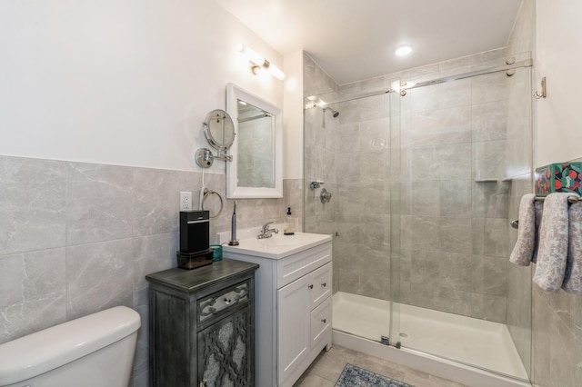 bathroom featuring walk in shower, tile patterned floors, toilet, tile walls, and vanity