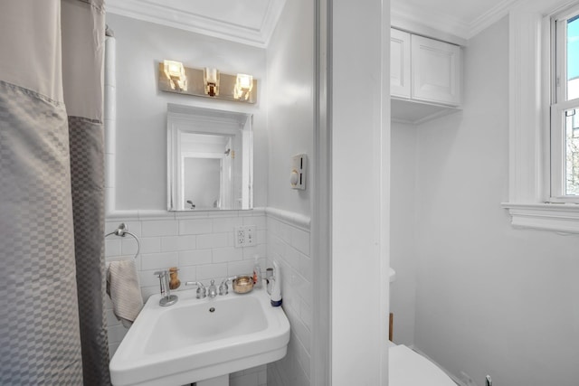 bathroom with toilet, tile walls, crown molding, and sink