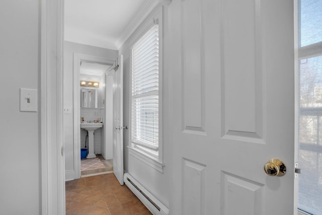 corridor featuring baseboard heating, crown molding, plenty of natural light, and sink