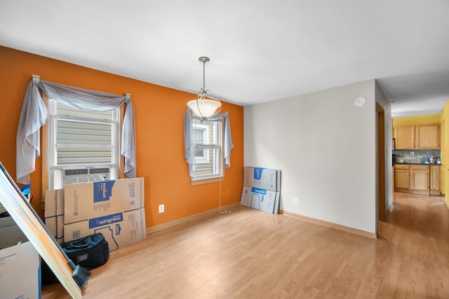 unfurnished room featuring light wood-type flooring, cooling unit, and baseboards