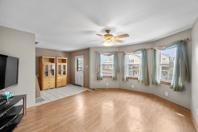 living area featuring baseboards, light wood-style flooring, and a ceiling fan