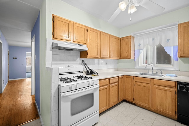 kitchen featuring white range with gas cooktop, dishwasher, light countertops, under cabinet range hood, and a sink