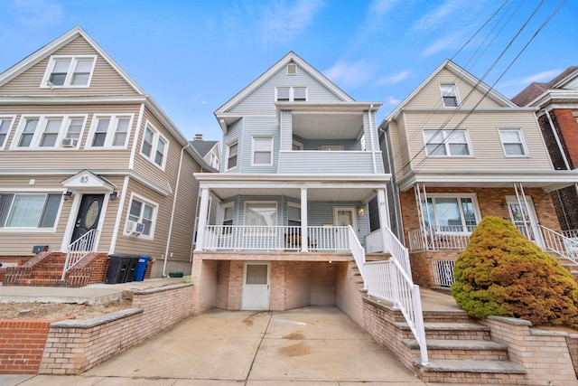 multi unit property with a balcony, a porch, and brick siding