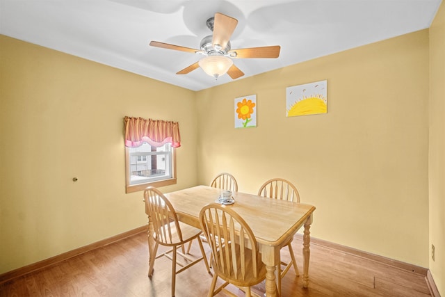 dining space with a ceiling fan, baseboards, and wood finished floors