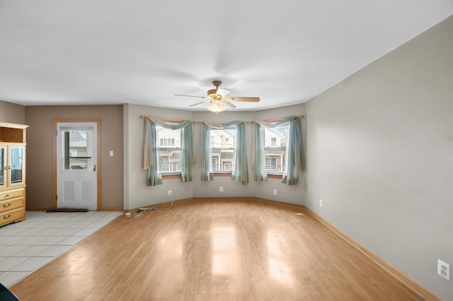 interior space featuring light wood-style floors, ceiling fan, and baseboards