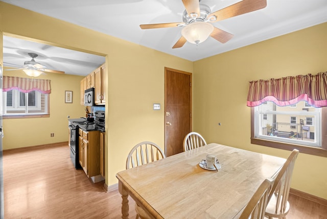 dining area featuring light wood-style floors, baseboards, and a ceiling fan