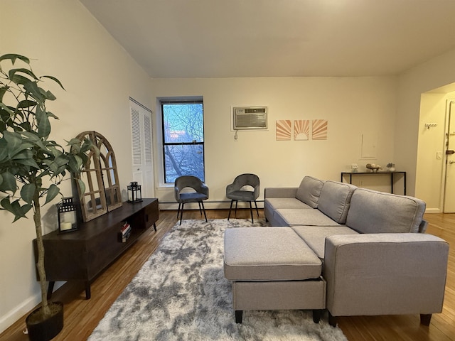 living room featuring a wall mounted air conditioner, hardwood / wood-style flooring, and a baseboard heating unit