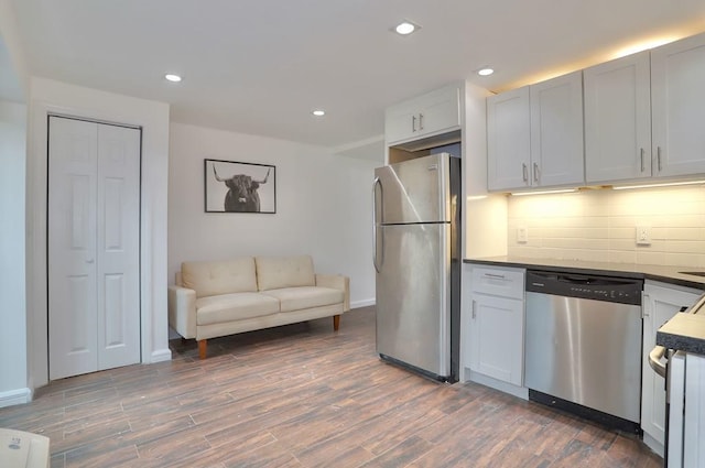 kitchen with stainless steel appliances, tasteful backsplash, dark countertops, and white cabinetry