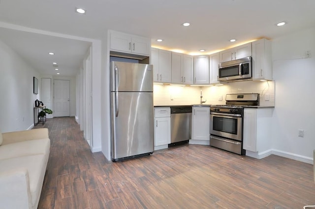 kitchen with dark wood finished floors, tasteful backsplash, dark countertops, appliances with stainless steel finishes, and white cabinetry