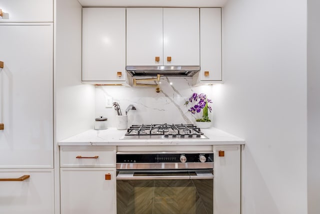 211 5th St Unit 1L, Jersey City, NJ 07302 - kitchen featuring appliances with stainless steel finishes, extractor fan, white cabinetry, tasteful backsplash, and light stone countertops