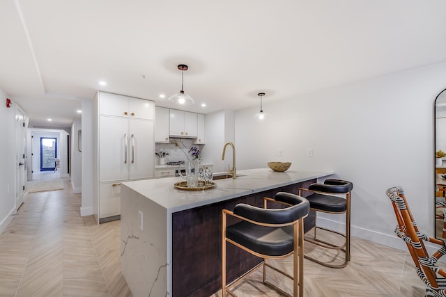 211 5th St Unit 1L, Jersey City, NJ 07302 - kitchen with a sink, paneled built in fridge, white cabinets, a breakfast bar area, and a peninsula