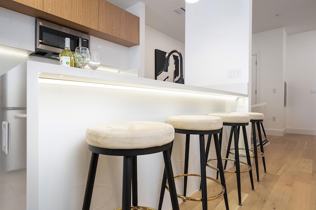 kitchen featuring kitchen peninsula, a breakfast bar area, and light wood-type flooring