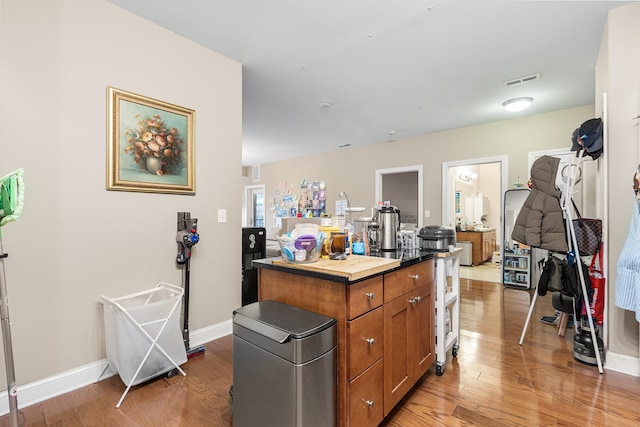 kitchen with baseboards, brown cabinets, a kitchen island, and light wood finished floors