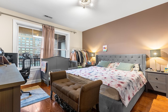 bedroom with visible vents, baseboards, and wood finished floors