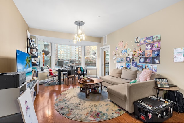 living room with visible vents, baseboards, an inviting chandelier, and wood finished floors