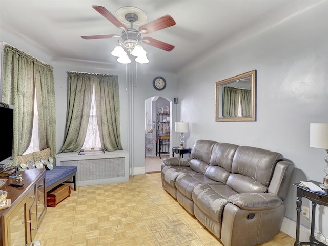 living room with arched walkways, a ceiling fan, and baseboards