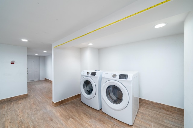 laundry area with light hardwood / wood-style floors and washer and clothes dryer