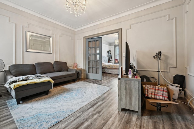 living room with a notable chandelier, crown molding, and wood-type flooring