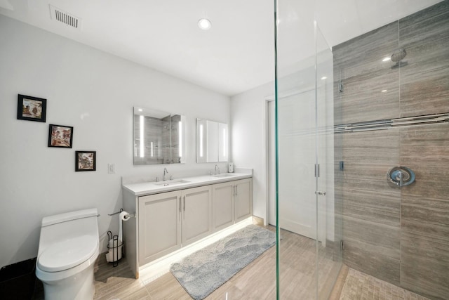 bathroom featuring toilet, vanity, an enclosed shower, and wood-type flooring